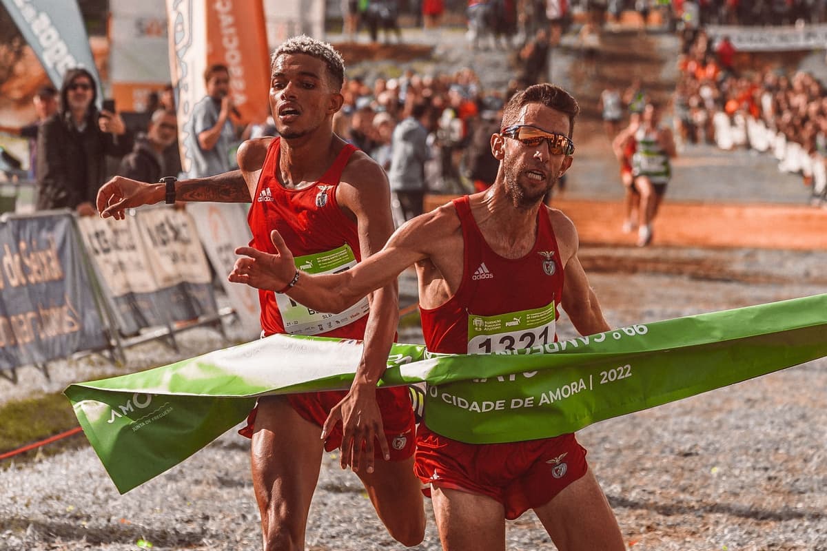 Two runners breaking the tape at a race finish line