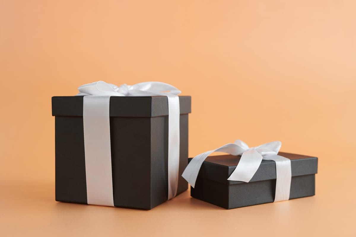Two black gift boxes tied with white ribbon