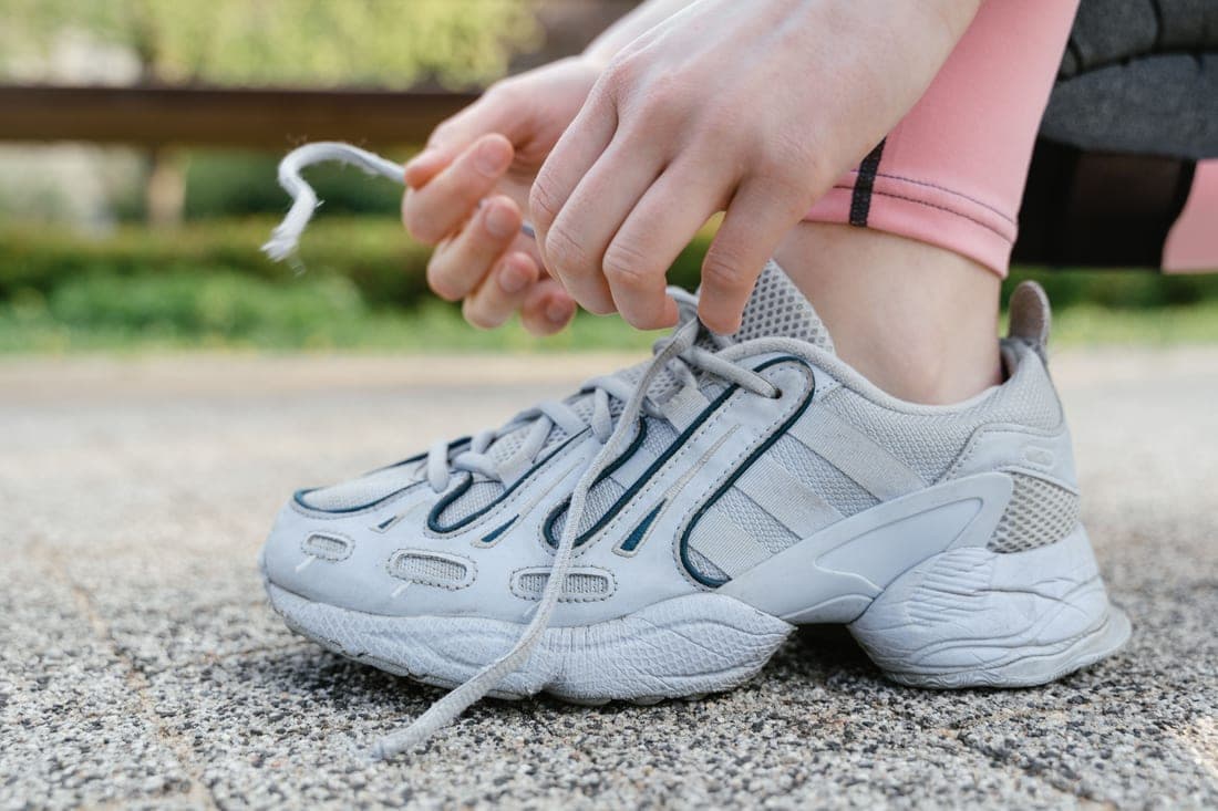 A runner tying the laces of a white running shoe