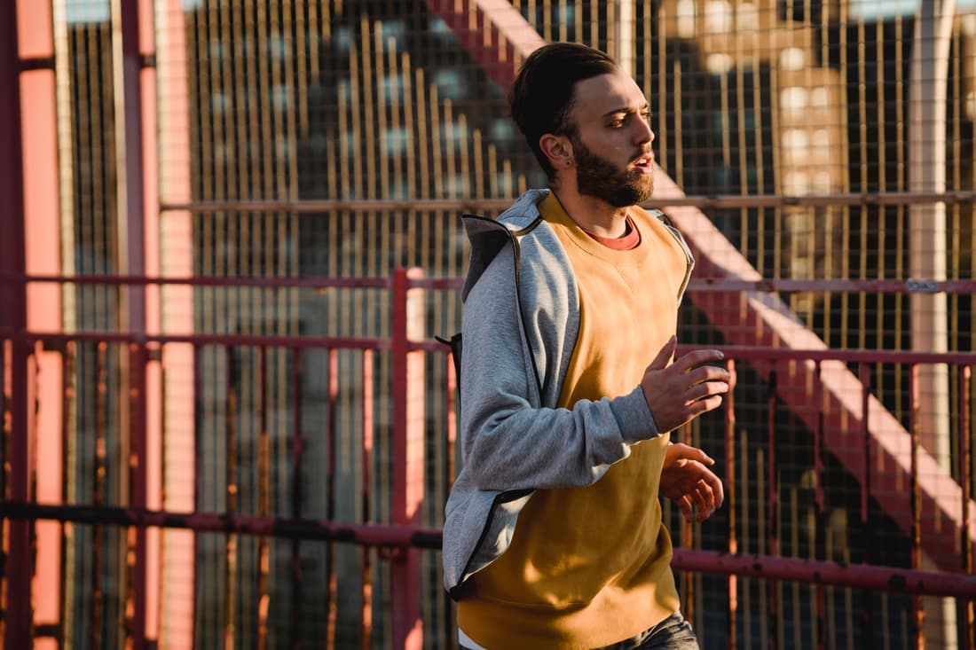 A man jogging across a city footbridge