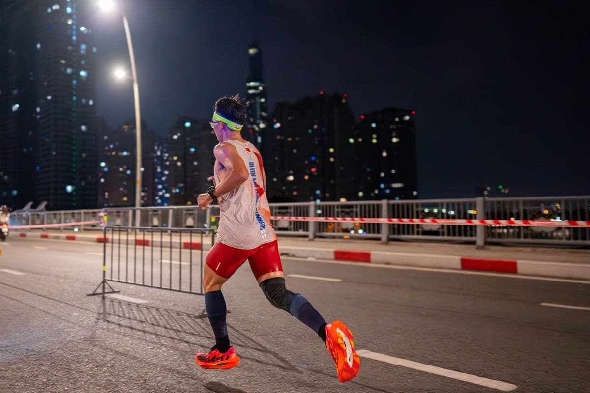 A runner in a night road race under city lights