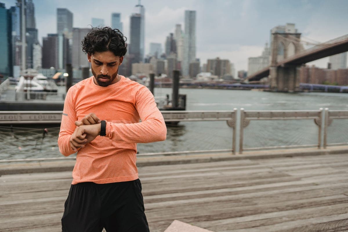 A runner checking his watch by a city waterfront
