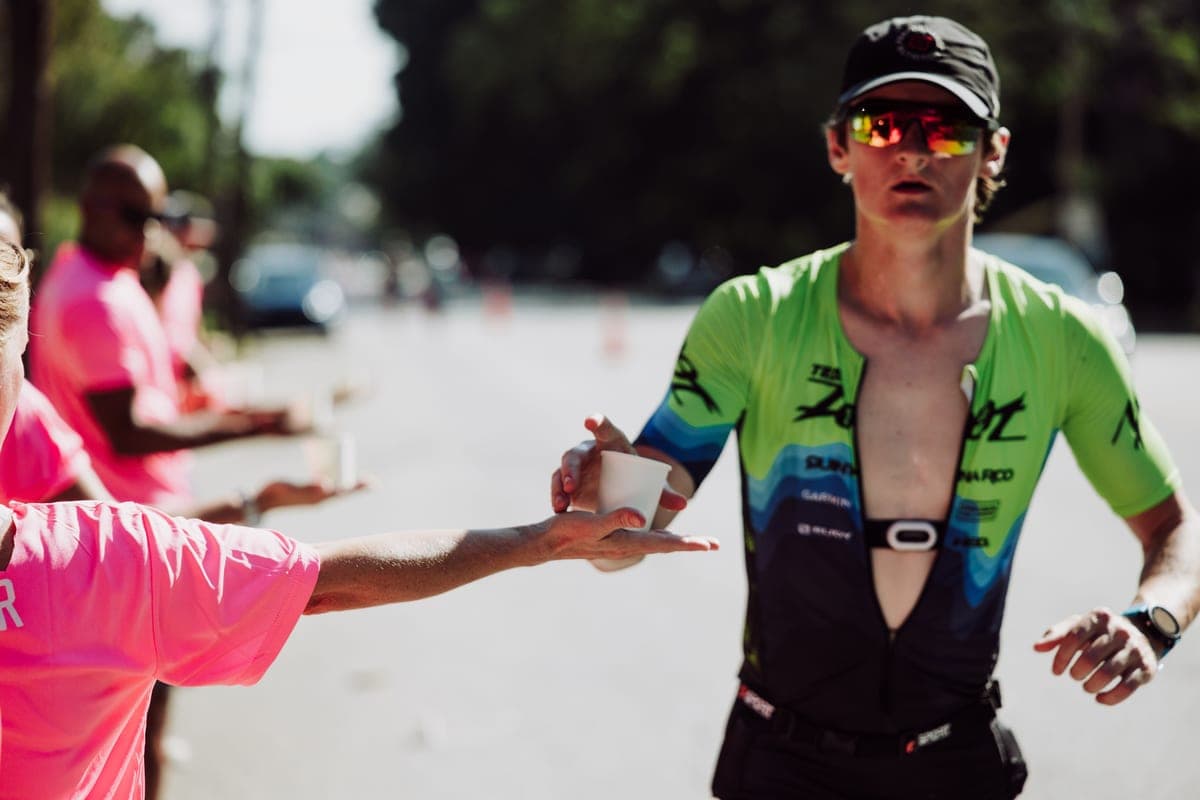 A runner taking a cup of water from a race volunteer