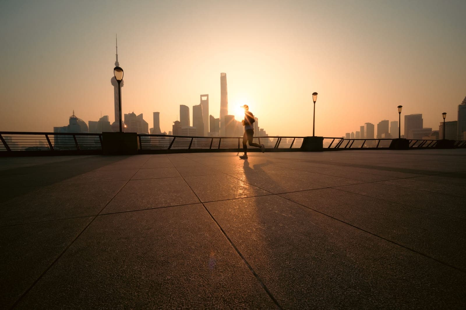 A runner silhouetted against a city skyline at sunrise