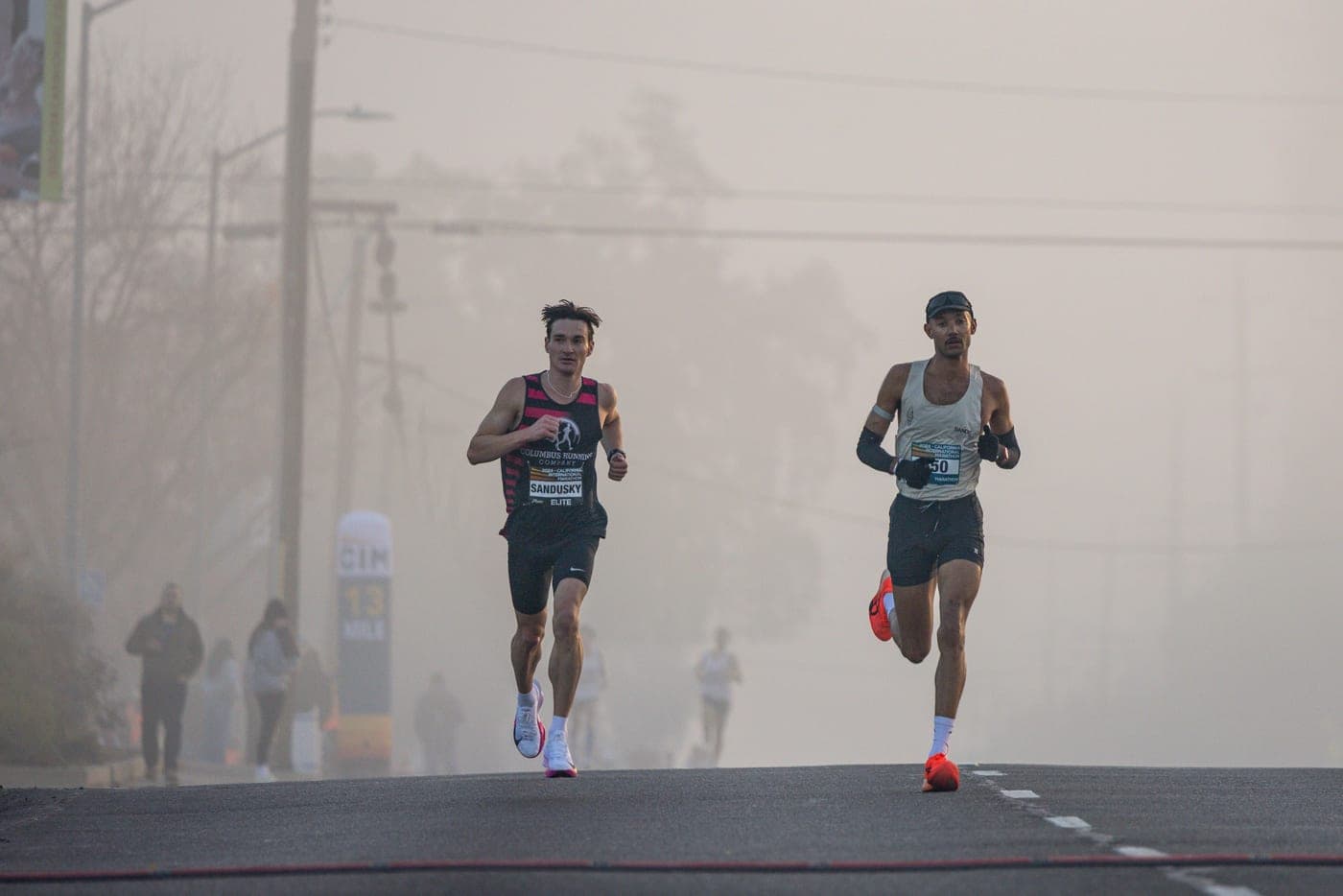 Two runners leading a road race on a foggy morning