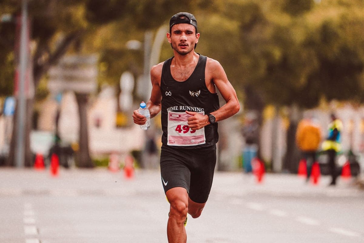 A road-race runner carrying a water bottle in one hand