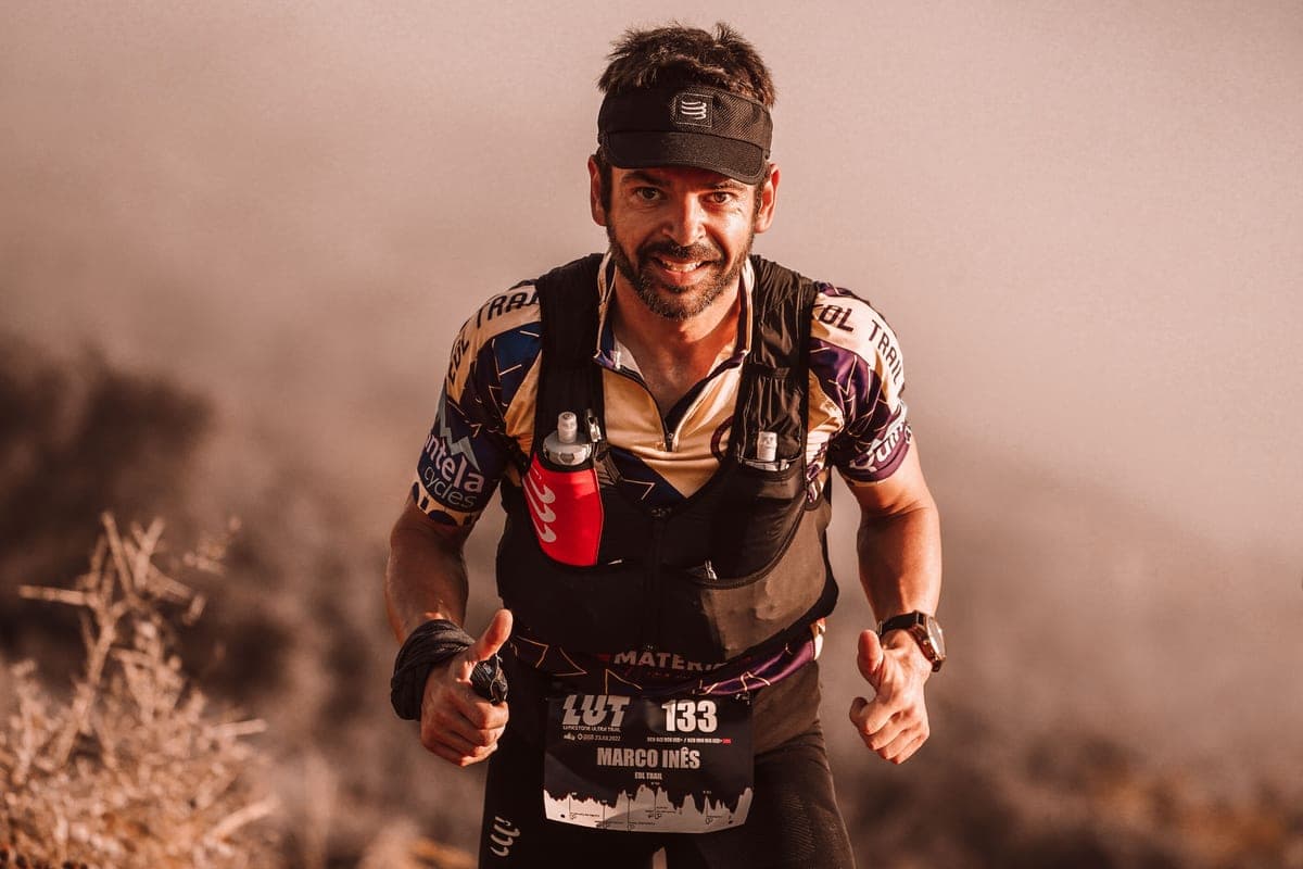 A trail race runner wearing a hydration vest with soft flasks