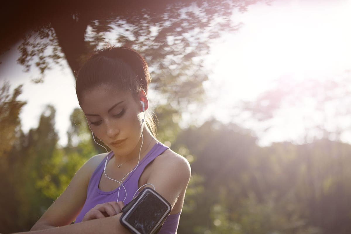 A runner adjusting a phone armband during a run in the park